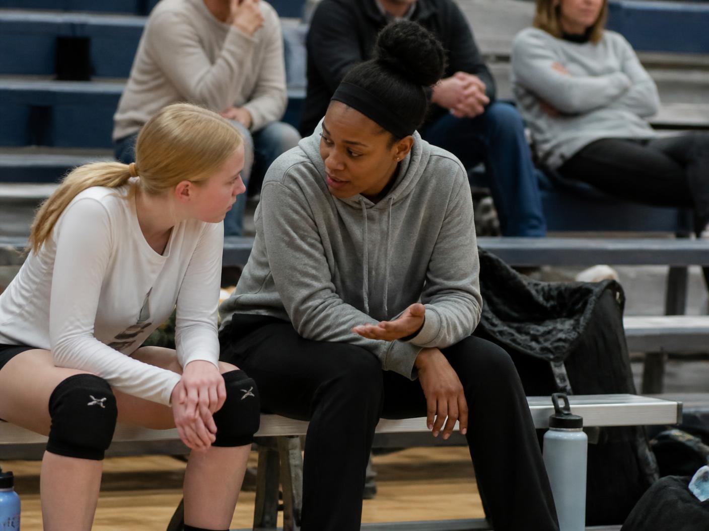 Volleyball coach talking quietly with a player on the sideline during practice
