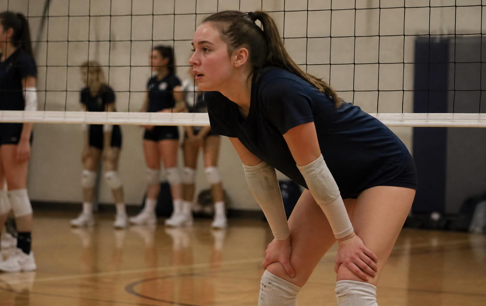 Teenage volleyball player standing near the net between points during club practice